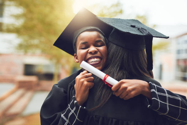 shot of two graduates embracing each other on graduation day